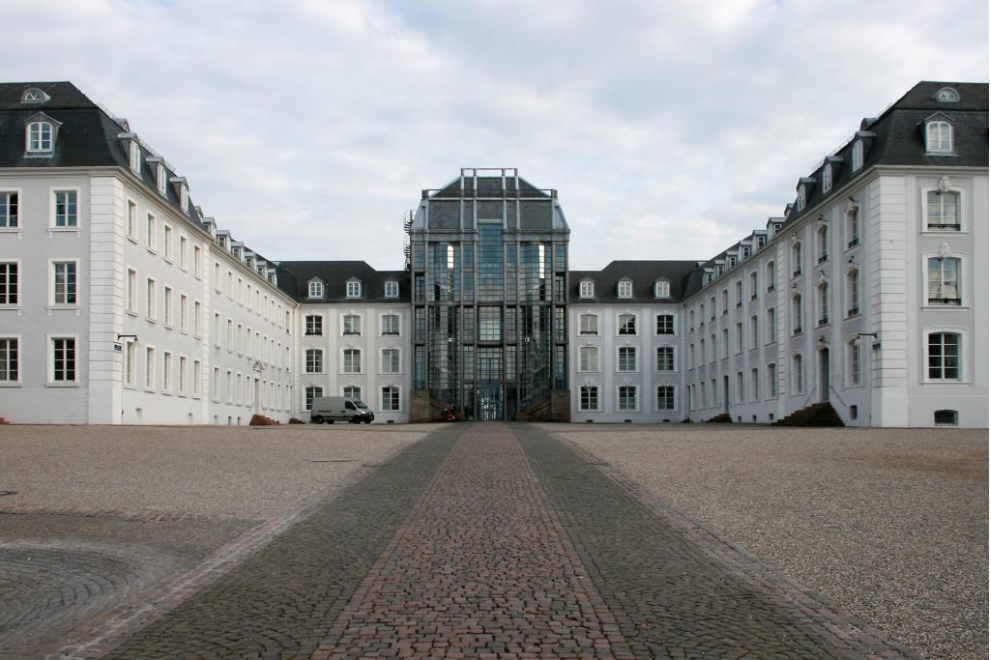  Une immense demeure avec une structure centrale en verre et de chaque côté, deux bâtiments blancs.