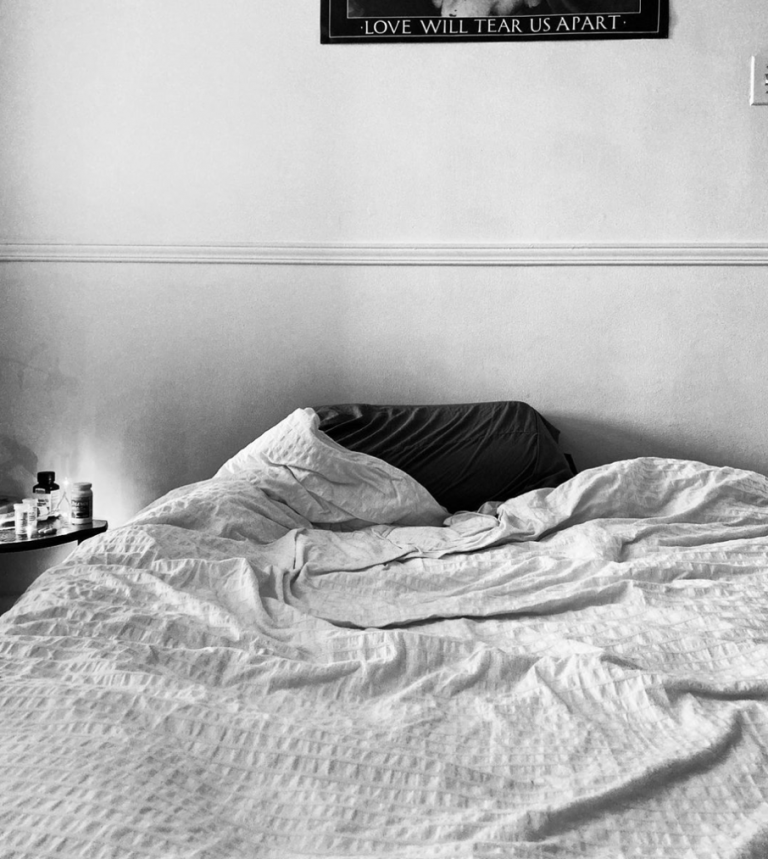 Photographie en noir et blanc d'un lit, où les traces de quelqu'un y paraissent encore.