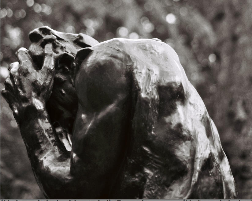 Photo en noir et blanc d'une sculpture d'un homme qui tient sa tête entre ses mains.